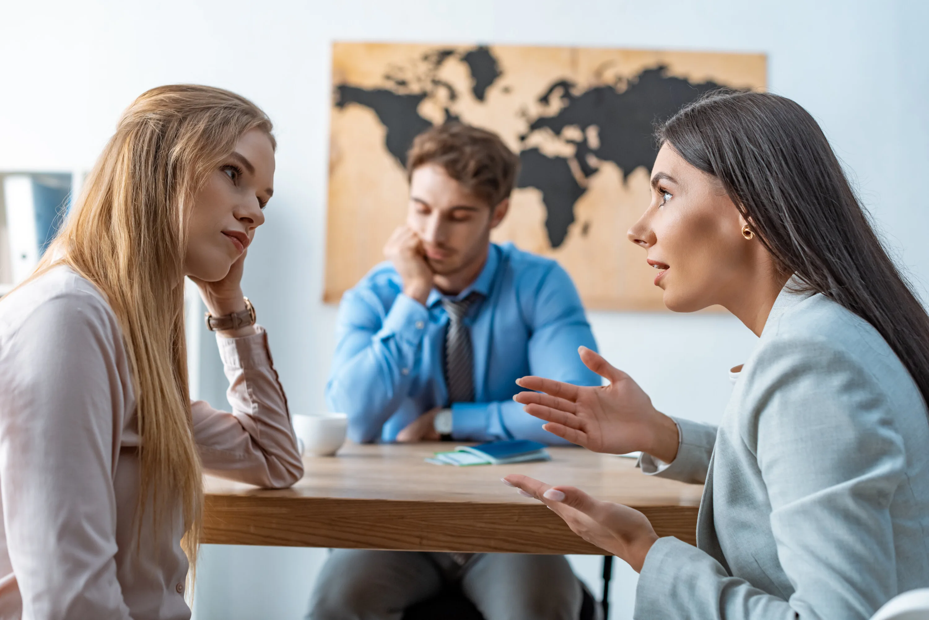 selective focus of disputing couple near bored travel agent